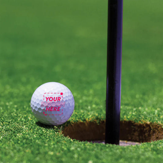 Close-up of a custom six-ball set with full-color logos arranged in a gift sleeve on a tee box at sunrise.