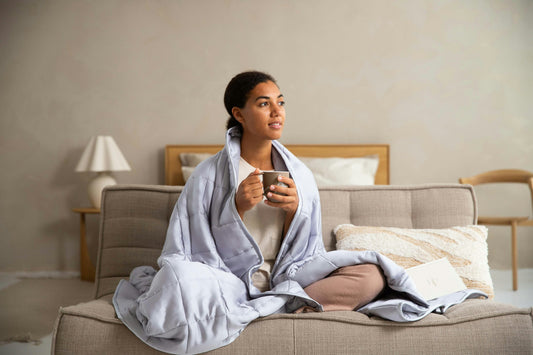 woman holding cup of tea under light blue blanket