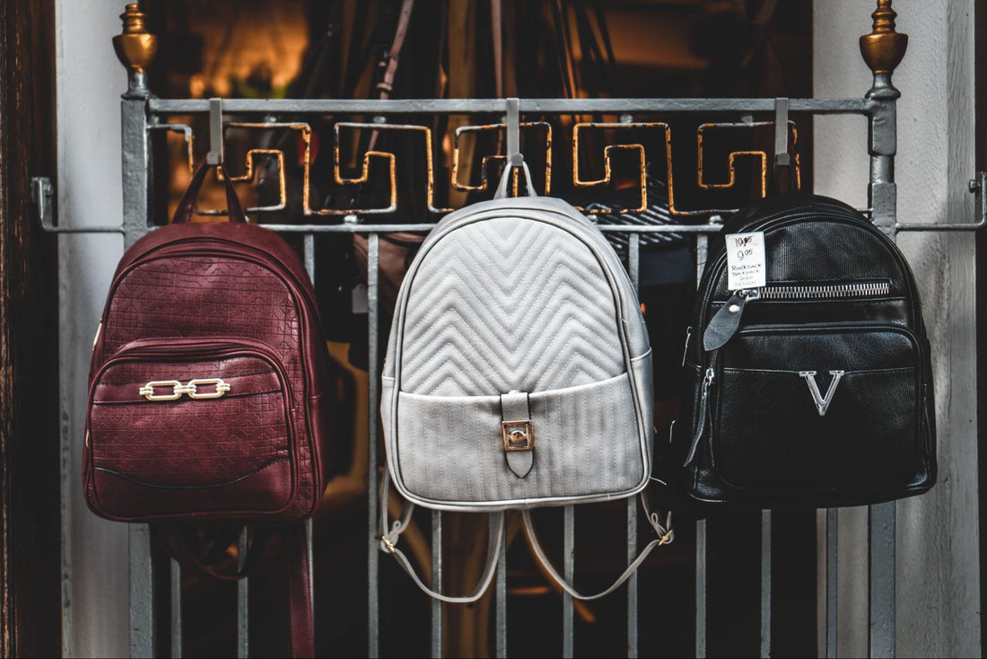 three custom print-on-demand backpacks hanged on a rail